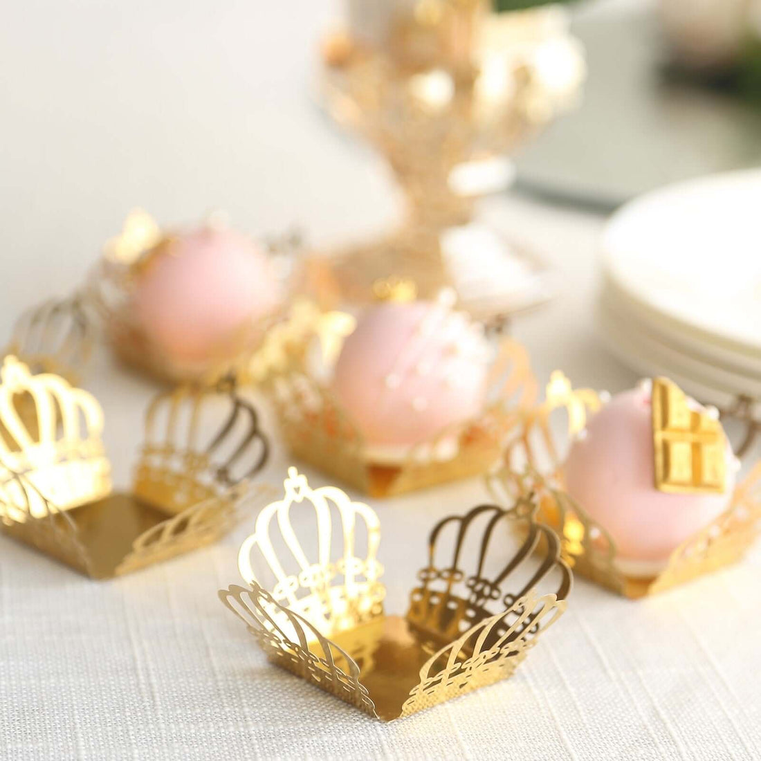 Gold crown-shaped dessert cups with pink sweets inside.