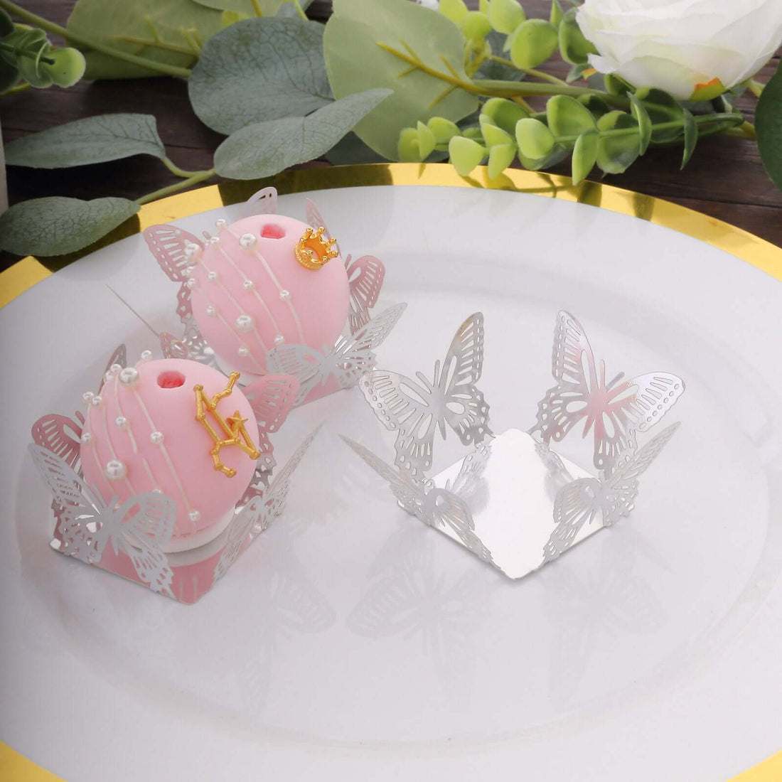Decorative pink and silver butterfly-themed candle holders on a plate.