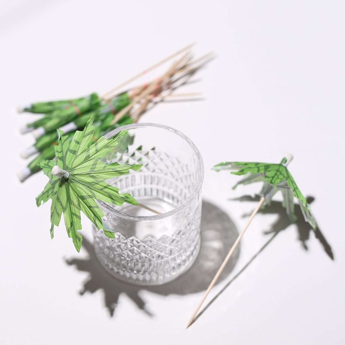 Paper cocktail umbrellas in glass with shadows