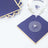 Navy blue coasters with gold edges and a glass of water on top.