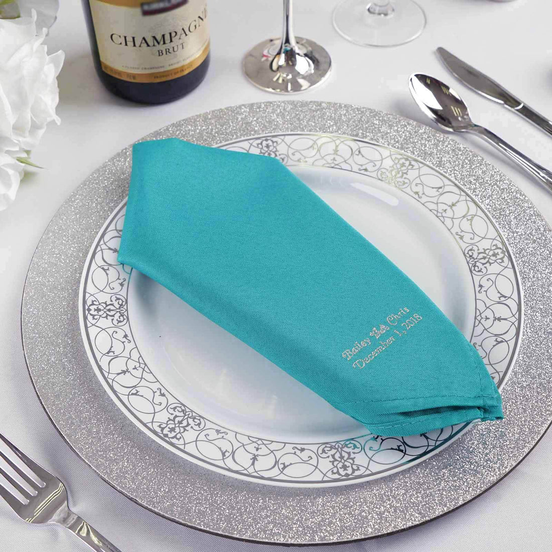 Turquoise napkin on a decorative plate for elegant dining setting.
