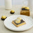 Chocolate truffles in gold packaging on a white plate.
