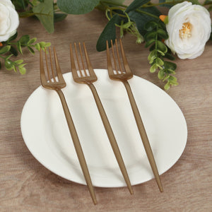 Set of three elegant gold plastic forks on a white plate.