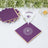 Purple coasters with gold trim under a glass of water on a table.