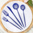 Blue plastic cutlery set on a white plate with wooden base.