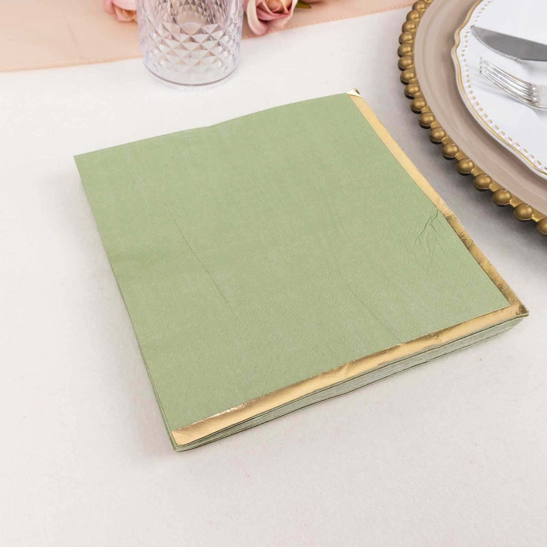 Green napkin with gold trim on a table setting.