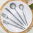 Gray cutlery set on a white plate with wooden serving board.