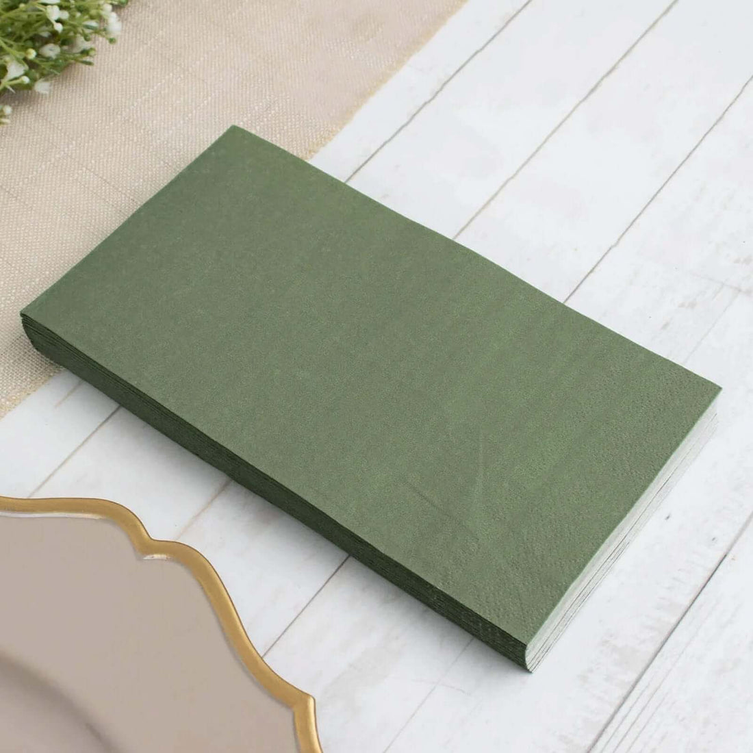 Green paper napkins stacked on a light wooden surface.