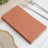 Rustic terracotta napkins stacked on a wooden table setting.