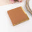Brown notepad with gold trim on a white surface.
