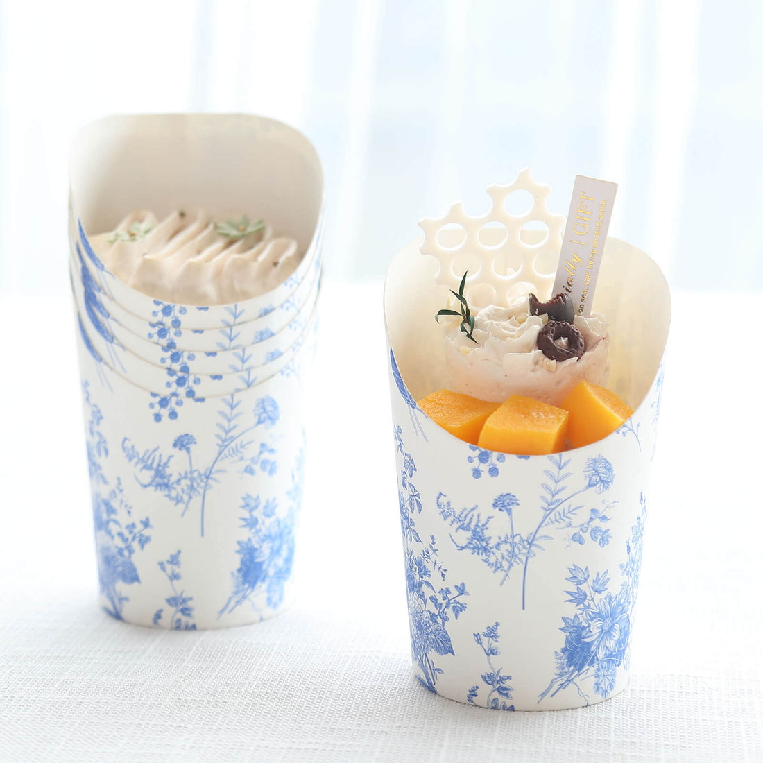 Decorative dessert cups with cream and fruit against a light background.
