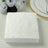 White embossed napkins stacked on a table with floral decor.