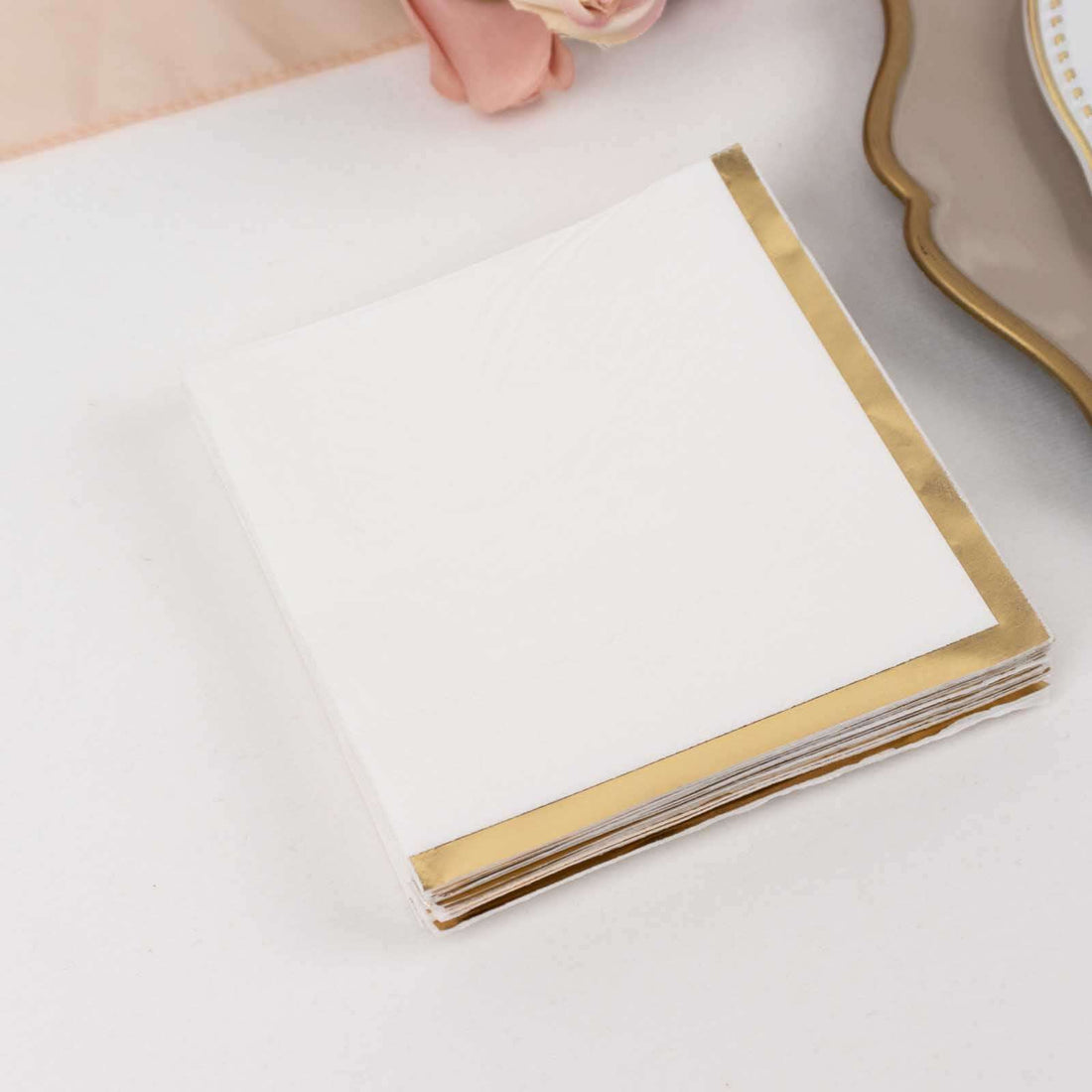 White napkins with gold foil edges on a plain background