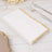 White menu with gold trim on a wooden table setting.