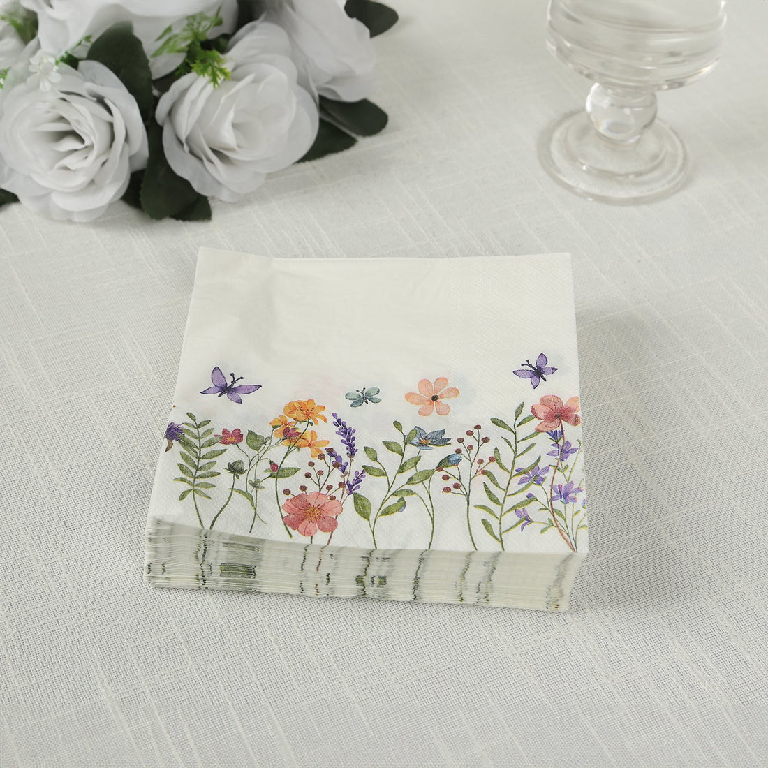 Floral paper napkins stacked on a table with decorative flowers.