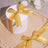 White gift box with yellow ribbon on a round tray with pearls