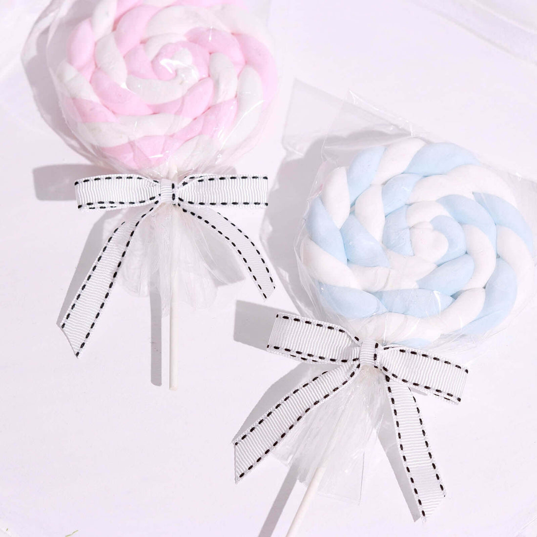 Colorful spiral lollipops wrapped in clear plastic with decorative bows.