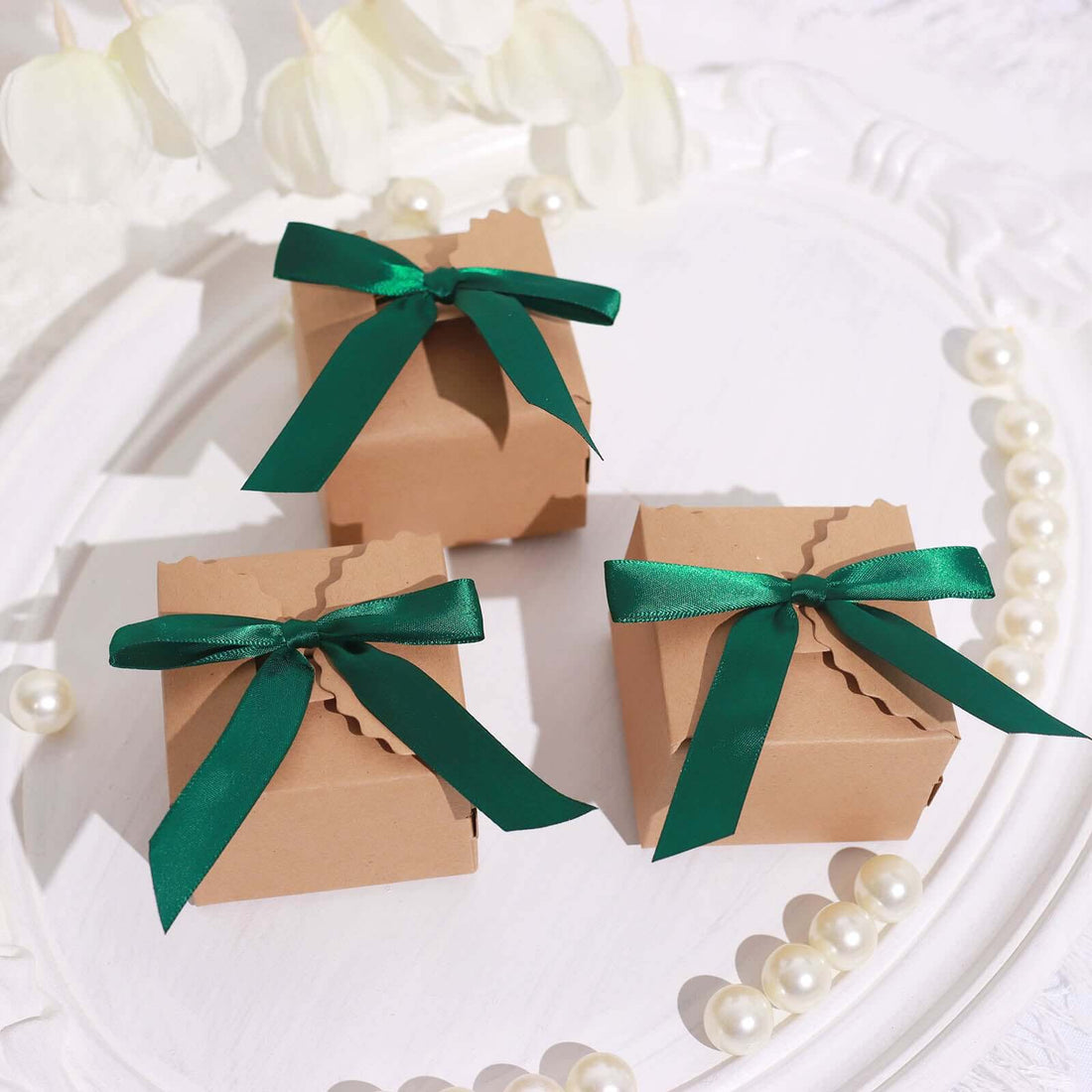Three gift boxes with green ribbons on a decorative white plate.