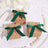 Three gift boxes with green ribbons on a decorative white plate.