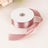 Pink satin ribbon on a spool with a loose end