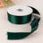 Green satin ribbon roll with a loose end on a plain backdrop.