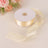 Cream satin ribbon roll with a loose end against a soft background.