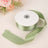 Green satin ribbon on a spool with a smooth finish.
