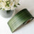 Green patterned ribbon roll beside a bouquet of white roses.