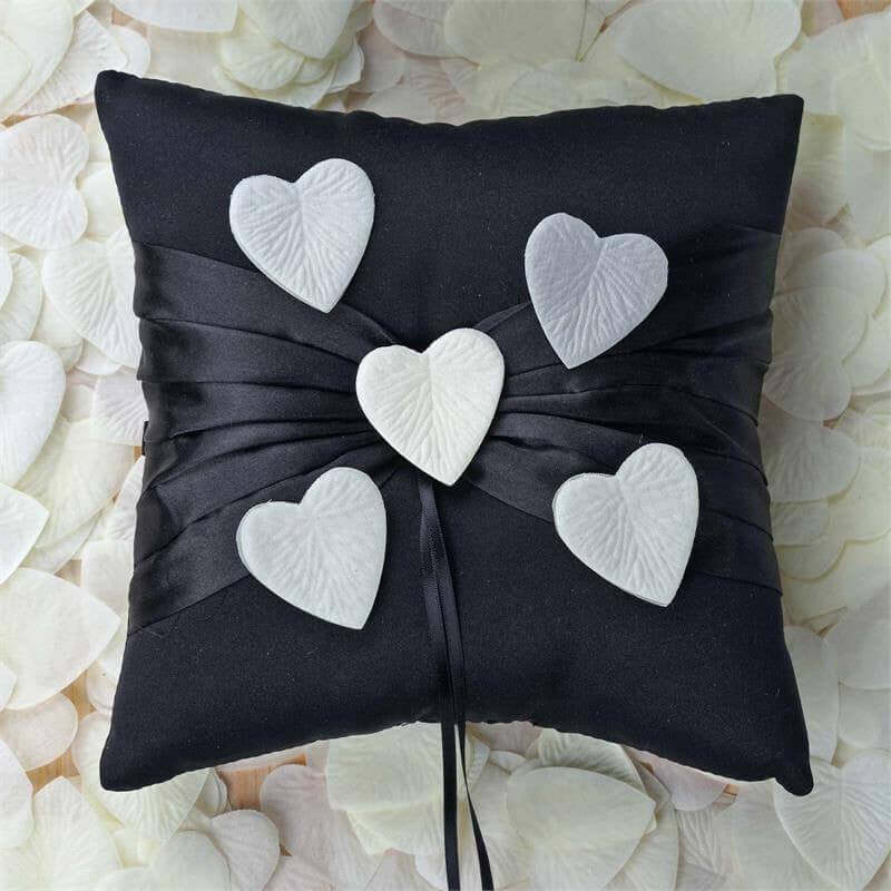 Black pillow adorned with heart-shaped decorations and satin ribbon.