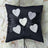 Black pillow adorned with heart-shaped decorations and satin ribbon.
