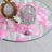 Decorative pink and white silk rose petals on a mirrored surface with a glass candle holder.