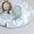 Clear glass tumbler on a mirrored surface surrounded by white rose petals.