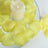 Yellow silk rose petals arranged around a candle on a reflective surface.
