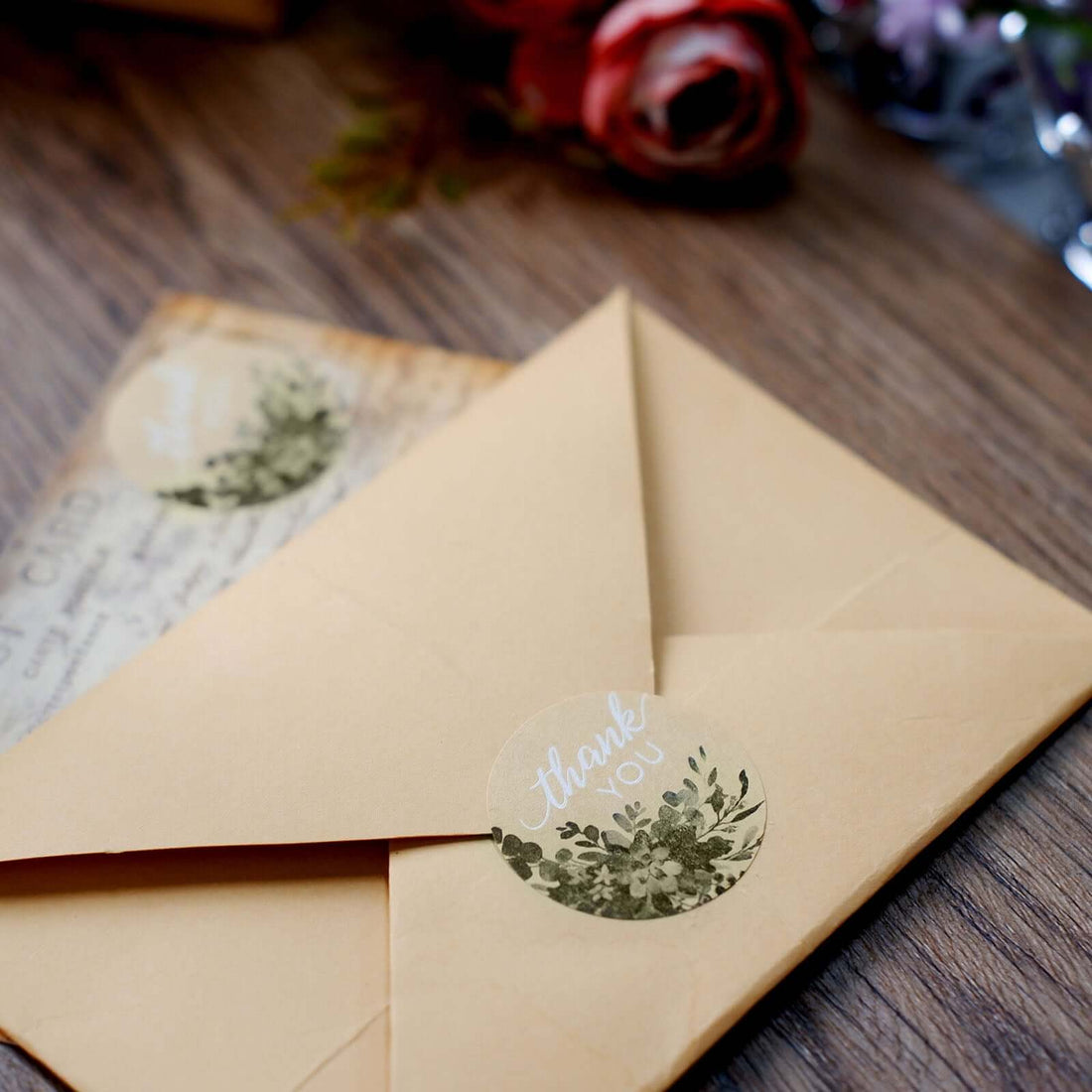 Thank you envelopes with floral stickers on a wooden surface.