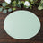 Green round placemat on a wooden table with decorative foliage.