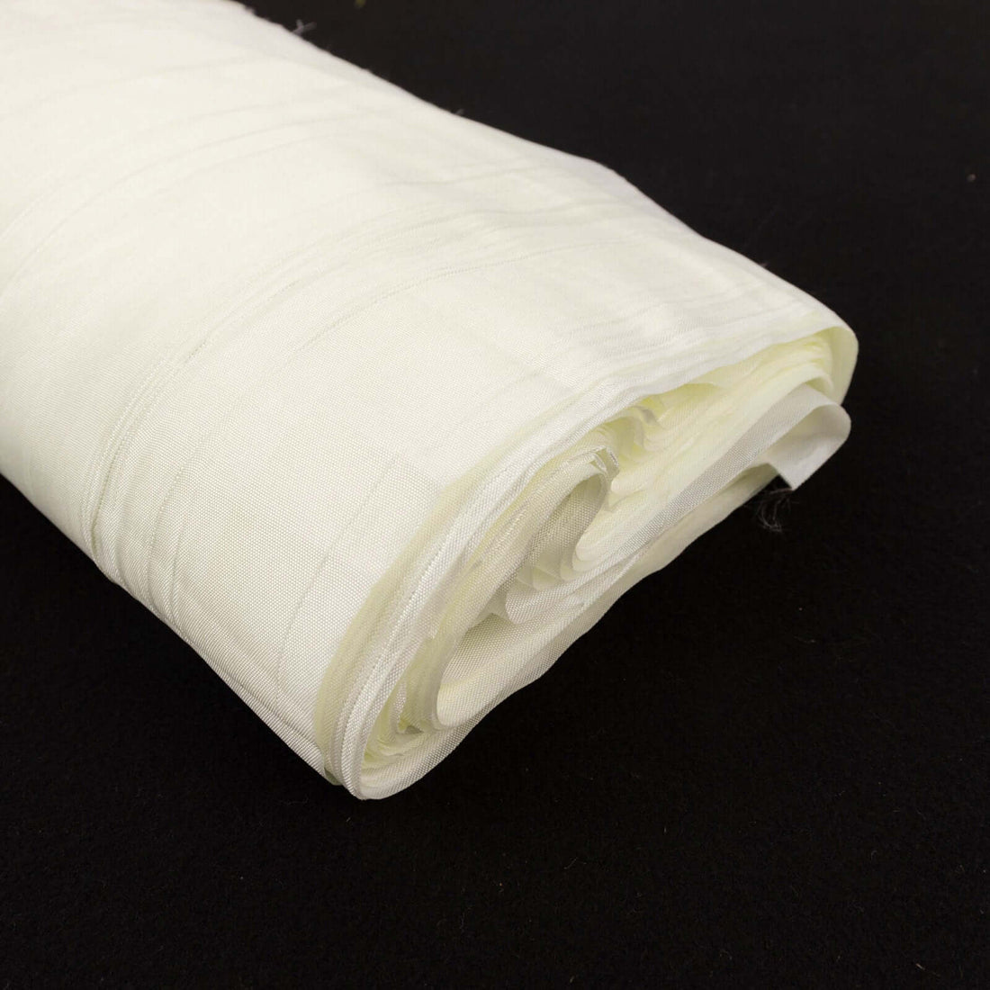 Rolled white fabric on a black background.