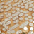 Gold sequin circular embellishments on a textured fabric surface. #whtbkgd