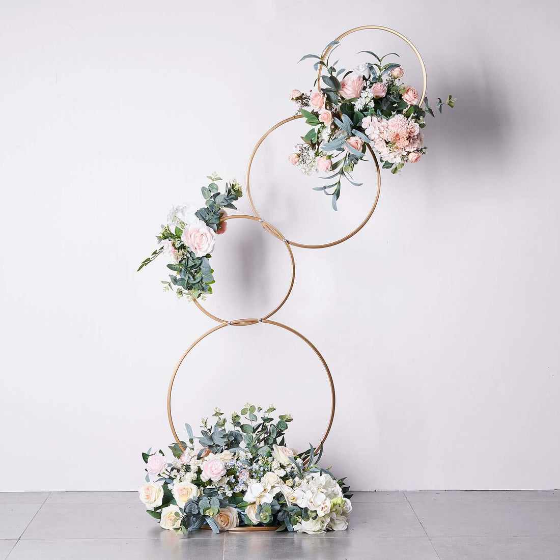 Floral arrangement with gold rings and pastel flowers on a white background