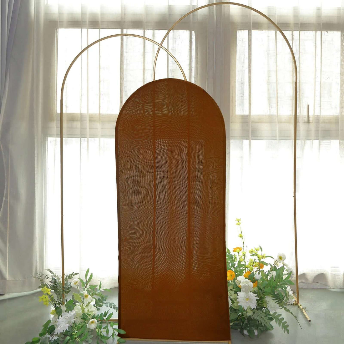 Brown fabric backdrop with arched frame and floral decorations.