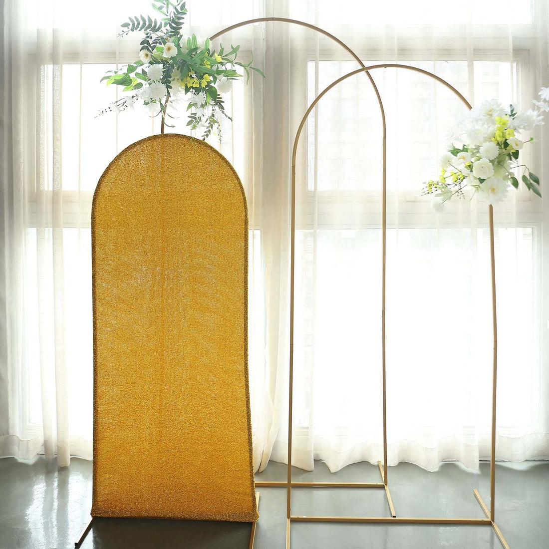 Gold arch backdrop with floral arrangements for events or photography.