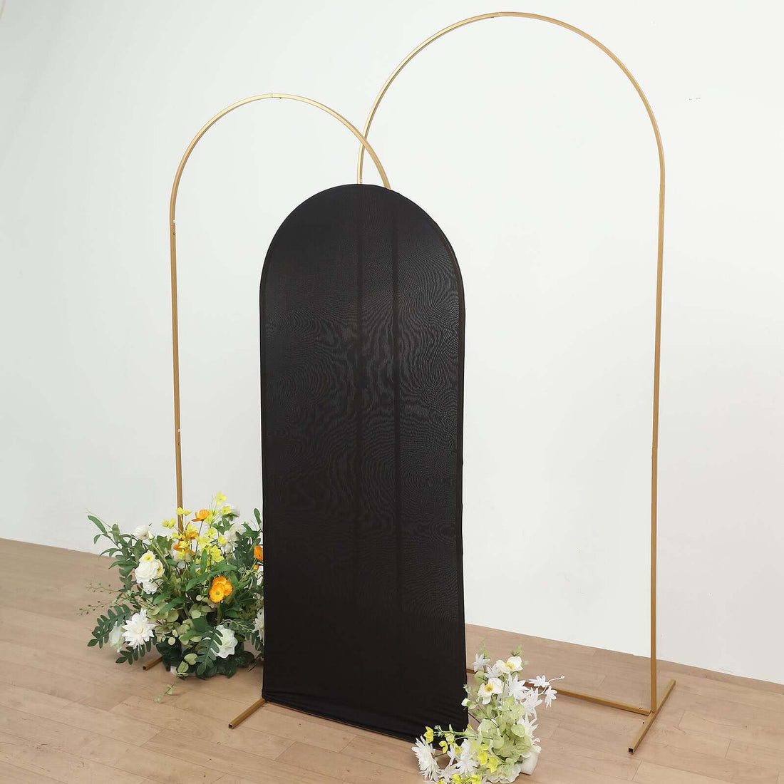 Black backdrop with gold arch stands and floral arrangements