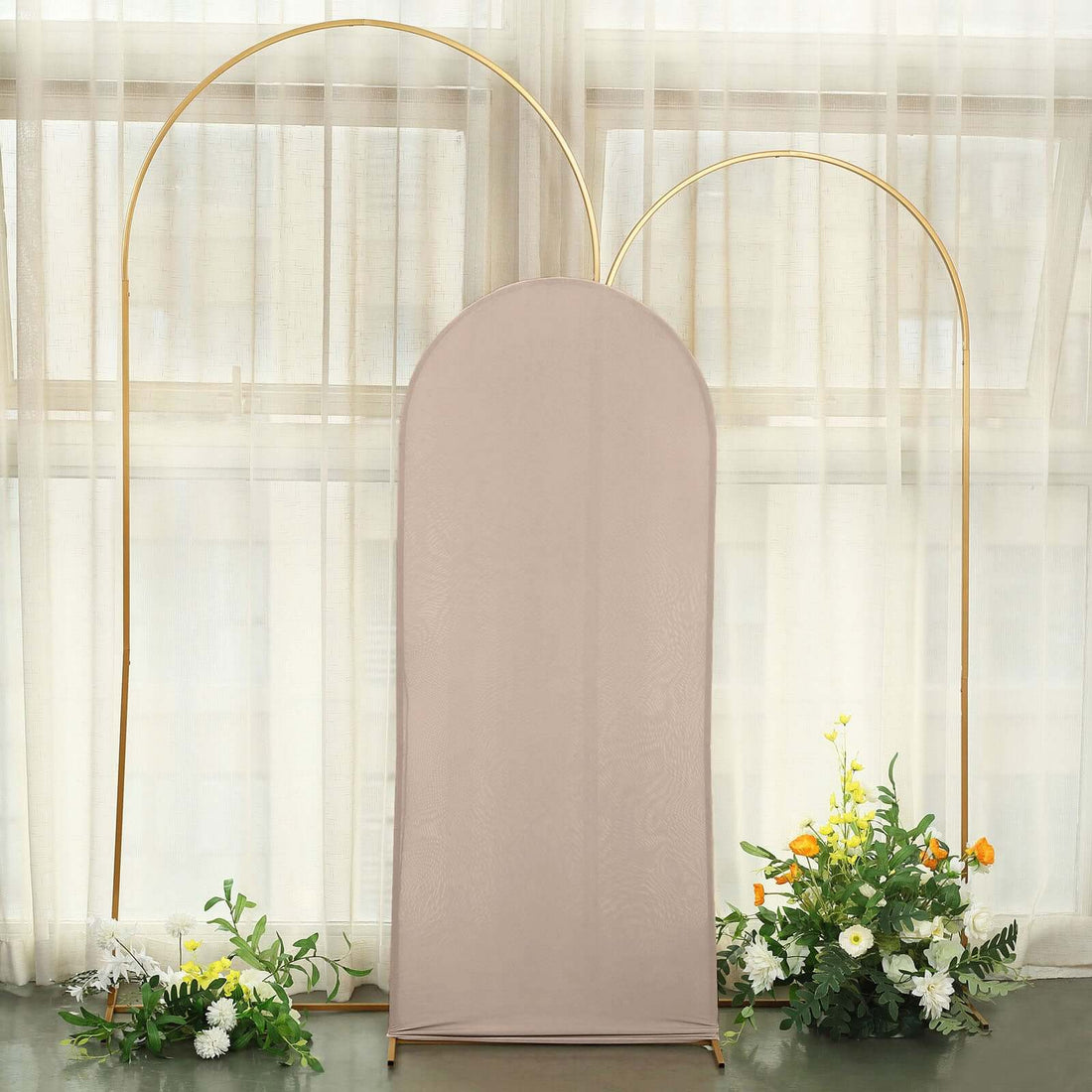 Soft beige backdrop with gold arches and floral arrangements.