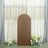 Brown backdrop with gold arch and floral arrangement in soft interior setting.
