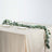 Eucalyptus table runner on beige table with plates and cutlery.