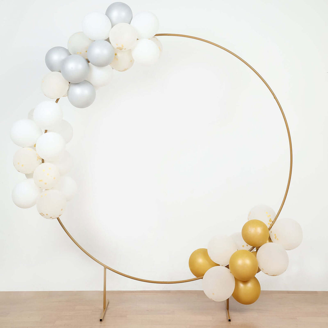 Gold and silver balloon arch with white accents on a plain backdrop
