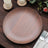 Brown wooden dinner plate on a rustic table with candles and greenery.