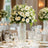 Elegant white floral arrangement in glass vase on dining table.