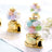 Miniature golden gumball machines filled with pastel gumballs.