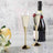 Elegant champagne flutes with gold accents beside a bottle of bubbly and flowers.