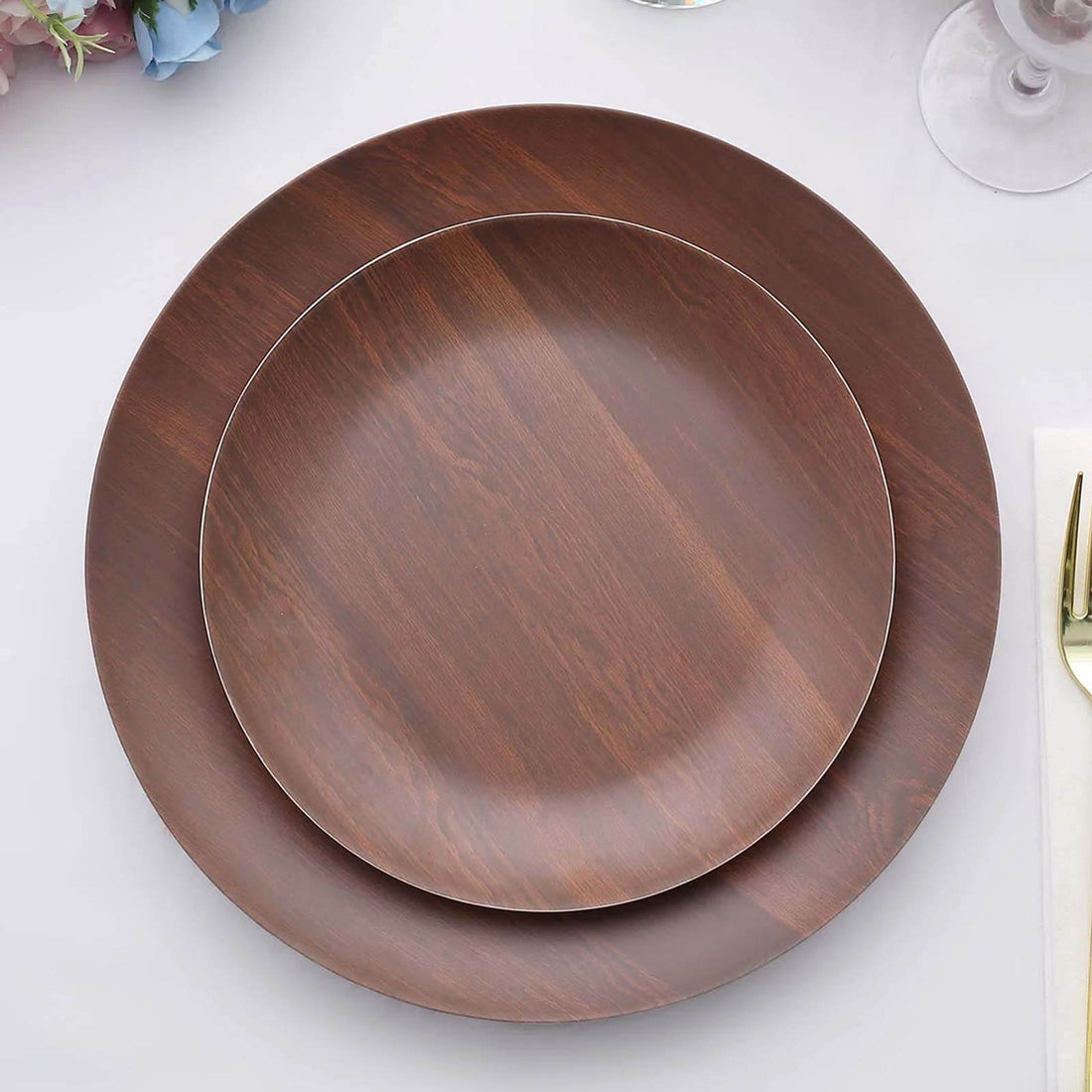 Brown wooden plates stacked on a table with elegant decor.
